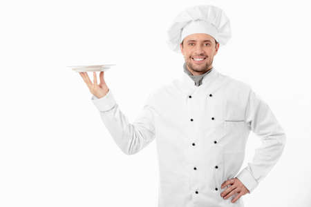 Smiling cook holding an empty plate on a white backgroundの写真素材