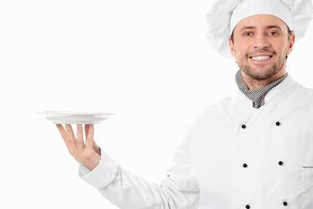 Attractive cook holding an empty plate on a white backgroundの写真素材