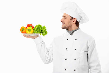 Happy cook holding a plate with vegetables on white backgroundの写真素材