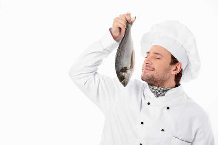 Cook holding a fresh fish on a white backgroundの写真素材