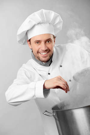 The cook prepares in the big pan from which there is steamの写真素材