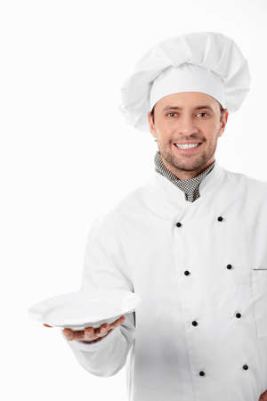 A smiling cook with a blank plate on a white backgroundの写真素材