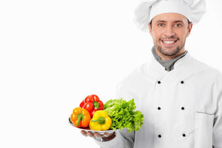 Attractive chef with a plate with vegetables on white backgroundの写真素材