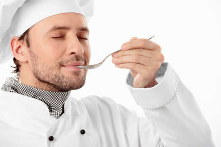 Attractive cook eat with a spoon with his eyes closed on a white backgroundの写真素材