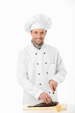 Cook cuts the fish on a white backgroundの写真素材