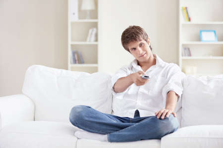 A young man switch TV channels at homeの写真素材