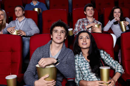 Young people are closely watching a movie at the cinemaの写真素材