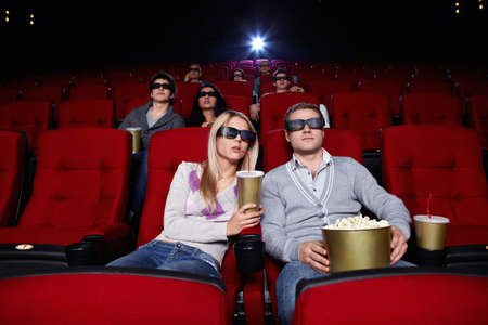 Young people watch movies in 3D glasses in cinemaの写真素材