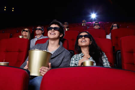 Funny people are watching a movie in 3D glasses in cinemaの写真素材