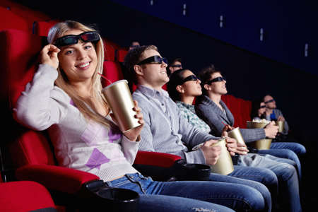Attractive girl looks into the camera from under the 3d glasses at the cinemaの写真素材