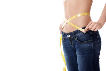 Girl in jeans measures the waist on a white backgroundの写真素材