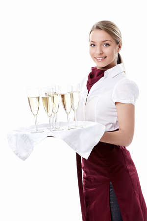 Young waitress carrying a tray with glasses of champagne on a white backgroundの写真素材