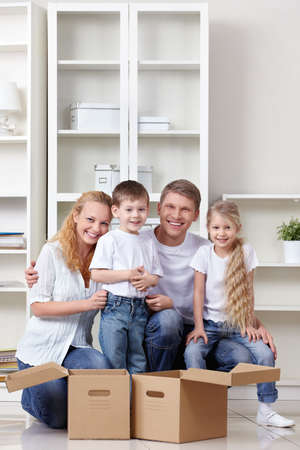 A happy family with kids and boxes indoorsの写真素材
