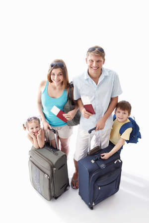 A happy family with their suitcases and passports to leave on a white backgroundの写真素材