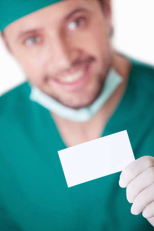 A young surgeon with a blank business card on a white backgroundの写真素材