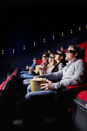 Young smiling people watch movies in cinemaの写真素材