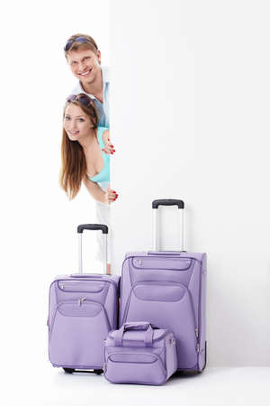 Young couple with suitcases and empty billboard on a white backgroundの写真素材