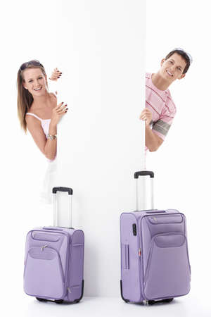 Young couple with suitcases and empty billboard on a white backgroundの写真素材
