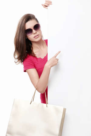 Beautiful girl with shopping bags and empty the board on a white backgroundの写真素材