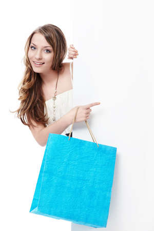 Young girl with shopping bags and empty the board on a white backgroundの写真素材