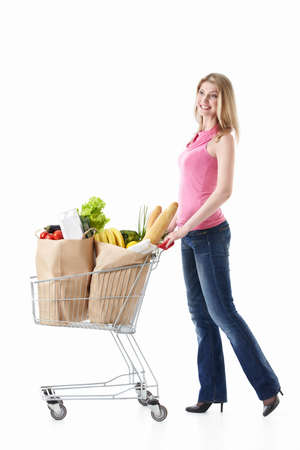 Happy girl with a cart with food on a white backgroundの写真素材