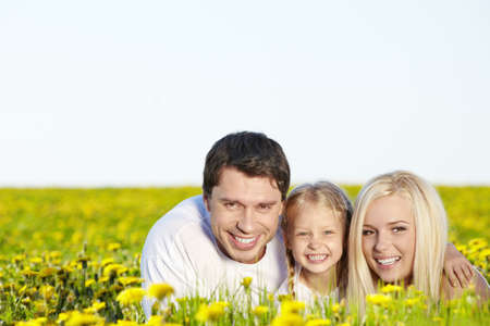 Happy young family in the dandelion fieldの写真素材