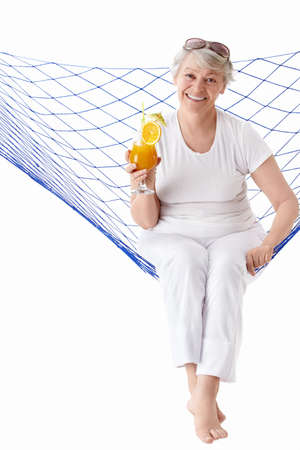 Mature woman with a cocktail in a hammock isolatedの写真素材