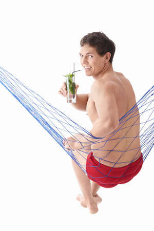 An attractive young man with a cocktail in a hammock isolatedの写真素材