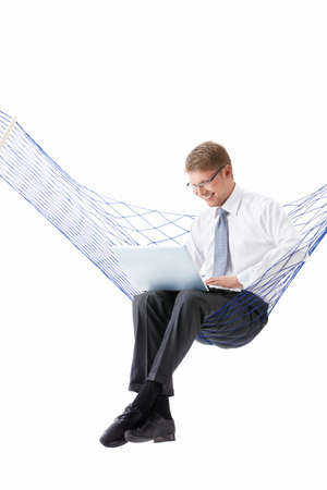 A young man with laptop in hammock isolatedの写真素材