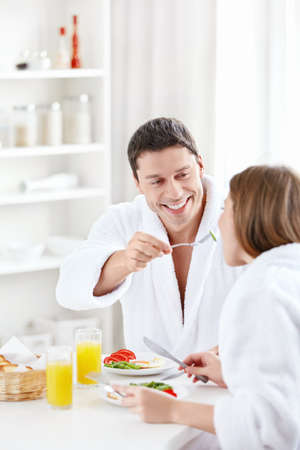 A young man feeds the woman in the kitchenの写真素材