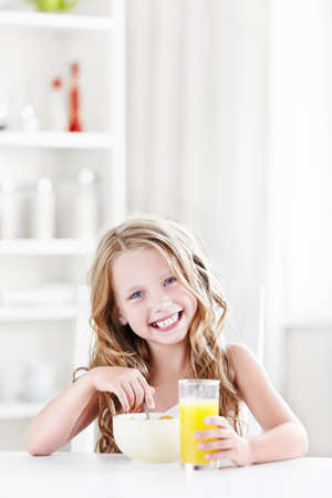 Little beautiful girl eats in the kitchenの写真素材