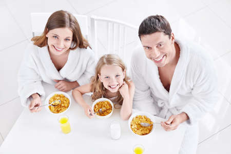 A happy family with a child eating breakfastの写真素材