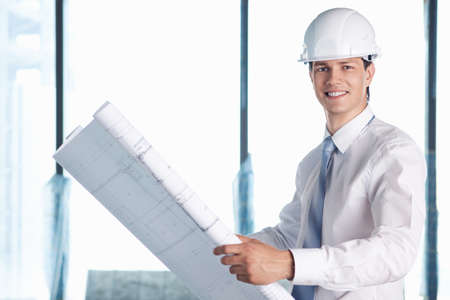 A man in a helmet with a plan for constructionの写真素材