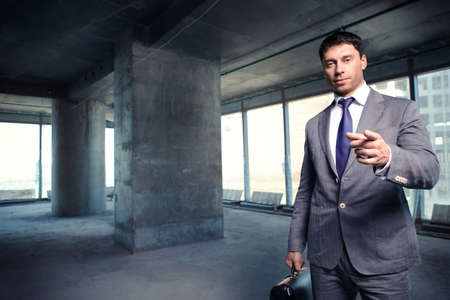 A man in a suit with a briefcase at a construction site