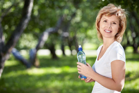 Mature woman with a bottle of water in the parkの写真素材