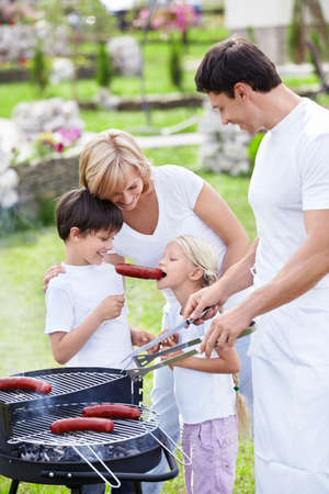 Happy family cooks sausages outdoorsの写真素材