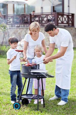 Happy family cooks sausages outdoorsの写真素材