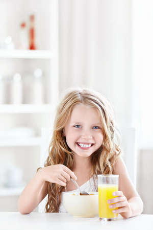 Beautiful little girl ate breakfast in the kitchenの写真素材