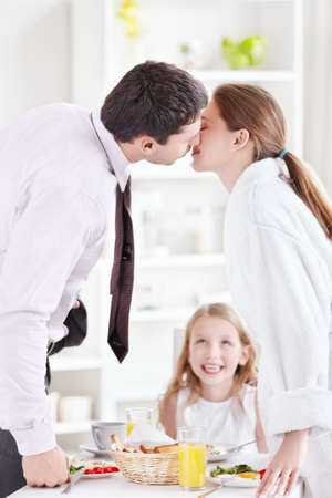 A couple kisses in front of the childの写真素材