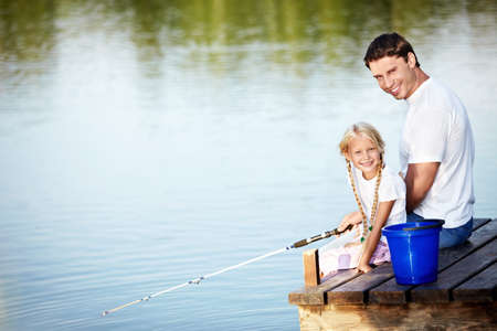 Father and daughter fishing on the lakeの写真素材