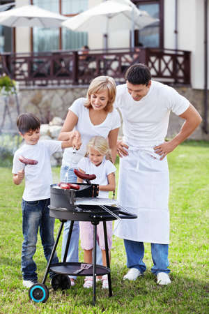 Happy family with barbecue outdoorsの写真素材
