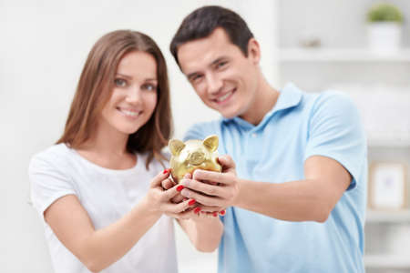 Young couple holding hands in the piggy bankの写真素材