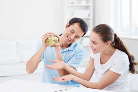 A man with a woman shaking a piggy bankの写真素材