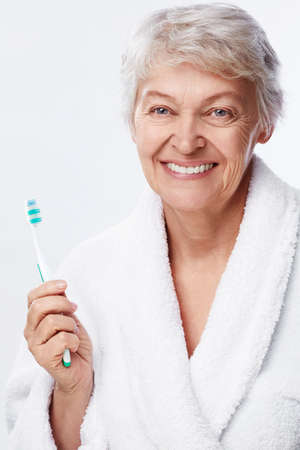 Elderly woman with a toothbrush on white backgroundの写真素材