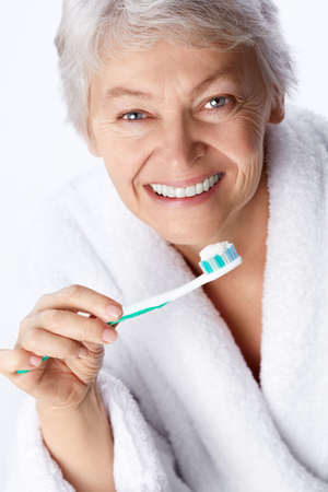 Elderly woman with a toothbrush on white backgroundの写真素材