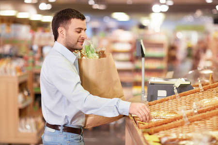 Young man with package of products in storeの写真素材