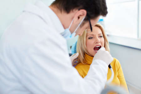 Stomatolog treats teeth patient in clinicの写真素材
