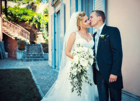 Groom kisses bride in a wedding dress at homeの写真素材