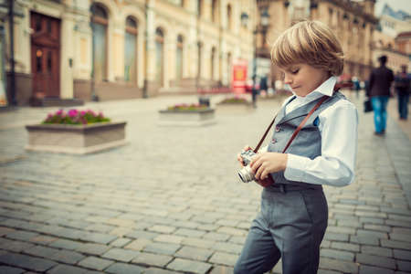 Little boy with a camera on the streetの写真素材