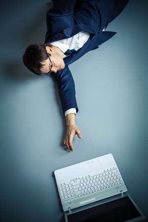 Businessman in suit stretches to laptopの写真素材